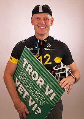 Marcus Matteby iklädd cykelkläder håller i en grön skylt med texten "Tror vi eller vet vi?".